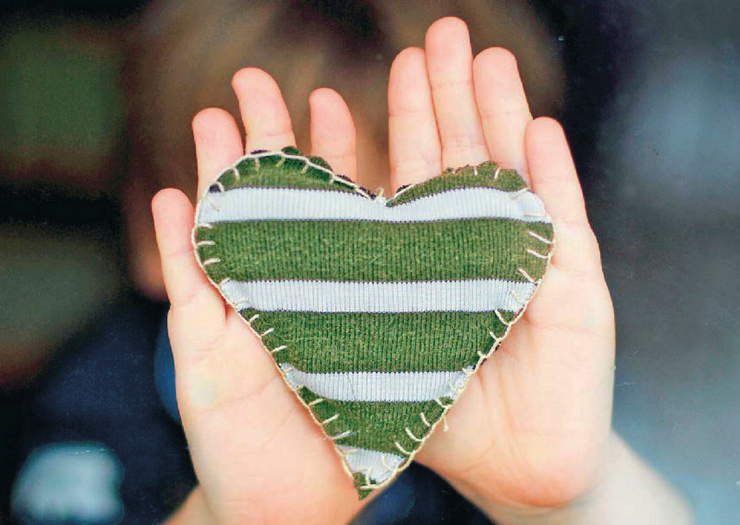 Barnhänder håller upp ett tyghjärta. 